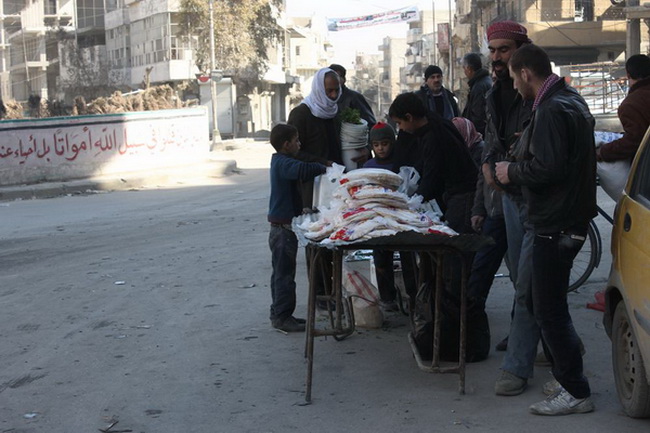 Дети окружены голодными покупателями, продавая хлеб в контролируемом повстанцами районе Алеппо.