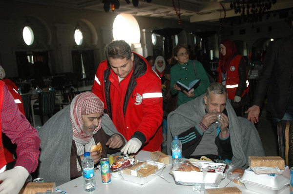 Распределение пищи среди людей, которые покидают старый город Хомса.