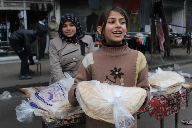 Две девочки продают хлеб на рынке аль-Хальванийя в Алеппо, самом большом городе страны.