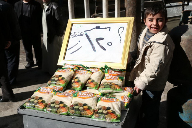 Ребенок раскладывает на прилавке пачки с индийским рисом в аль-Хальванийе, районе Алеппо.