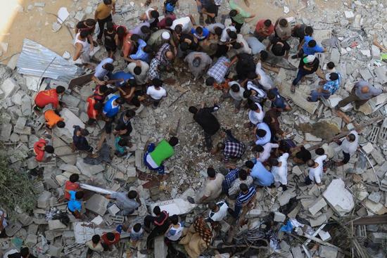 Палестинцы обследуют развалины разрушенного дома в районе Шейх Редван, что в городе Газа, 21 июля.