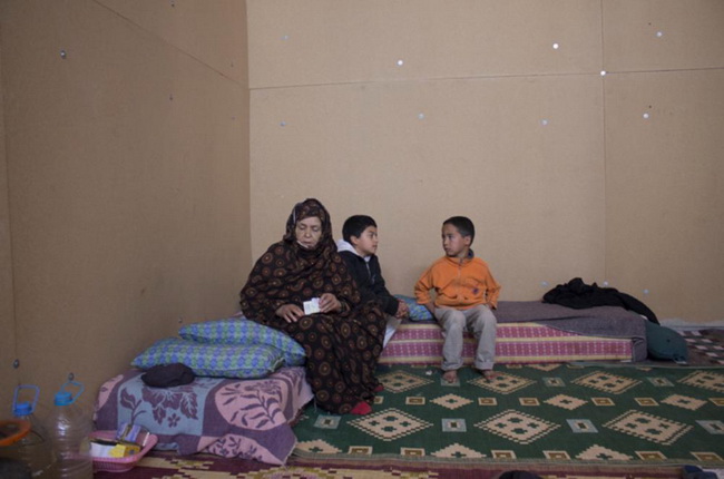 Женщина из Гуэльмима сидит внутри здания кооператива вместе со своими внуками. Она просит короля Марокко, Мухаммада VI, о помощи, после того, как лишилась всего, что имела.