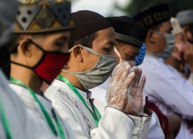 Индонезийские мусульмане носят защитные маскикогда молятся в мечети во время Ид аль-Фитр 24 мая 2020 года.